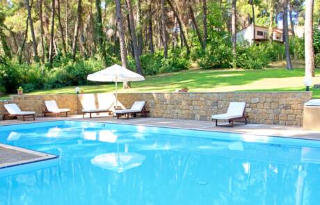 Swimming pool and surrounding space with umbrellas and sunbeds in Sani Cape Villas